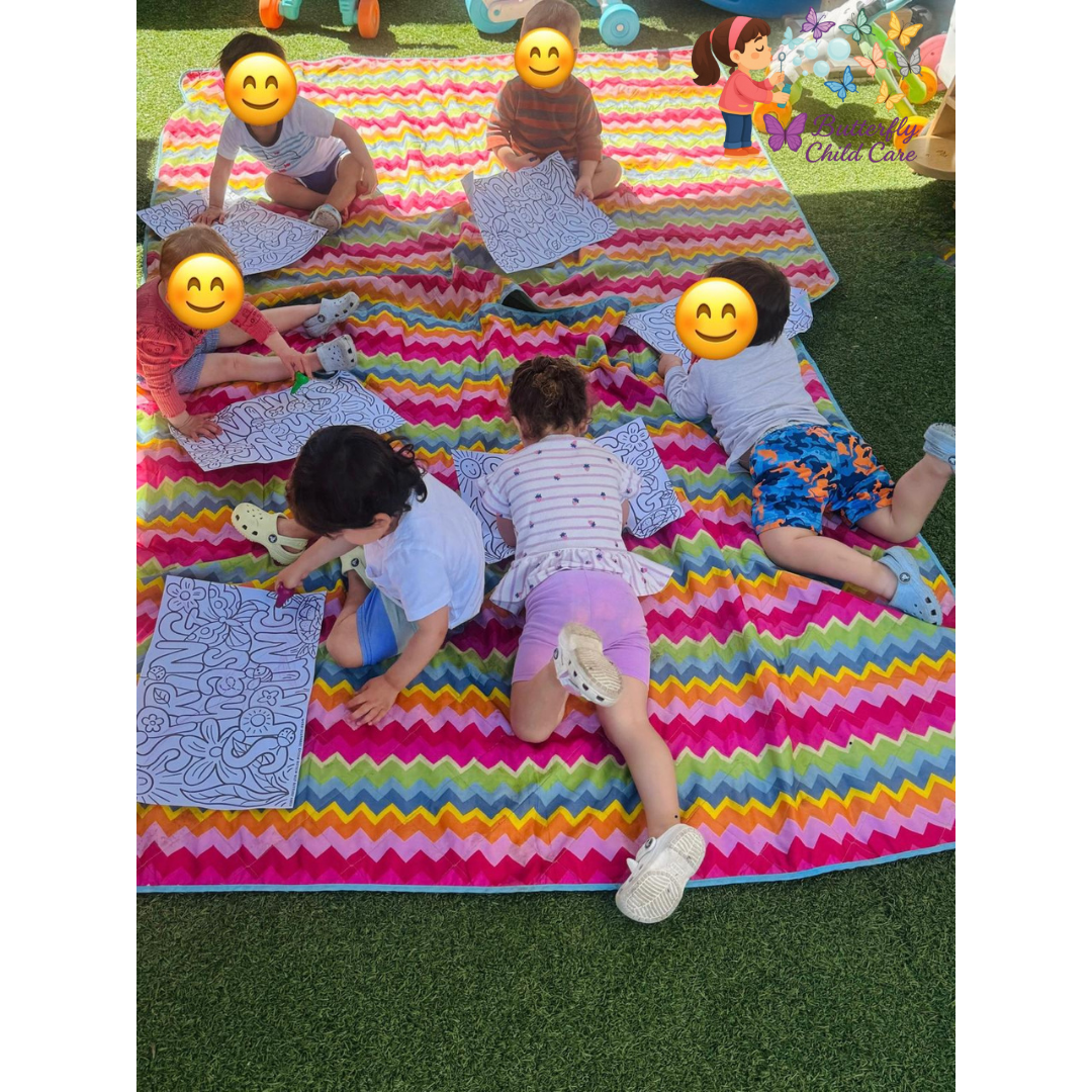 Children coloring outdoors on a colorful mat during an art activity at Butterfly Child Care