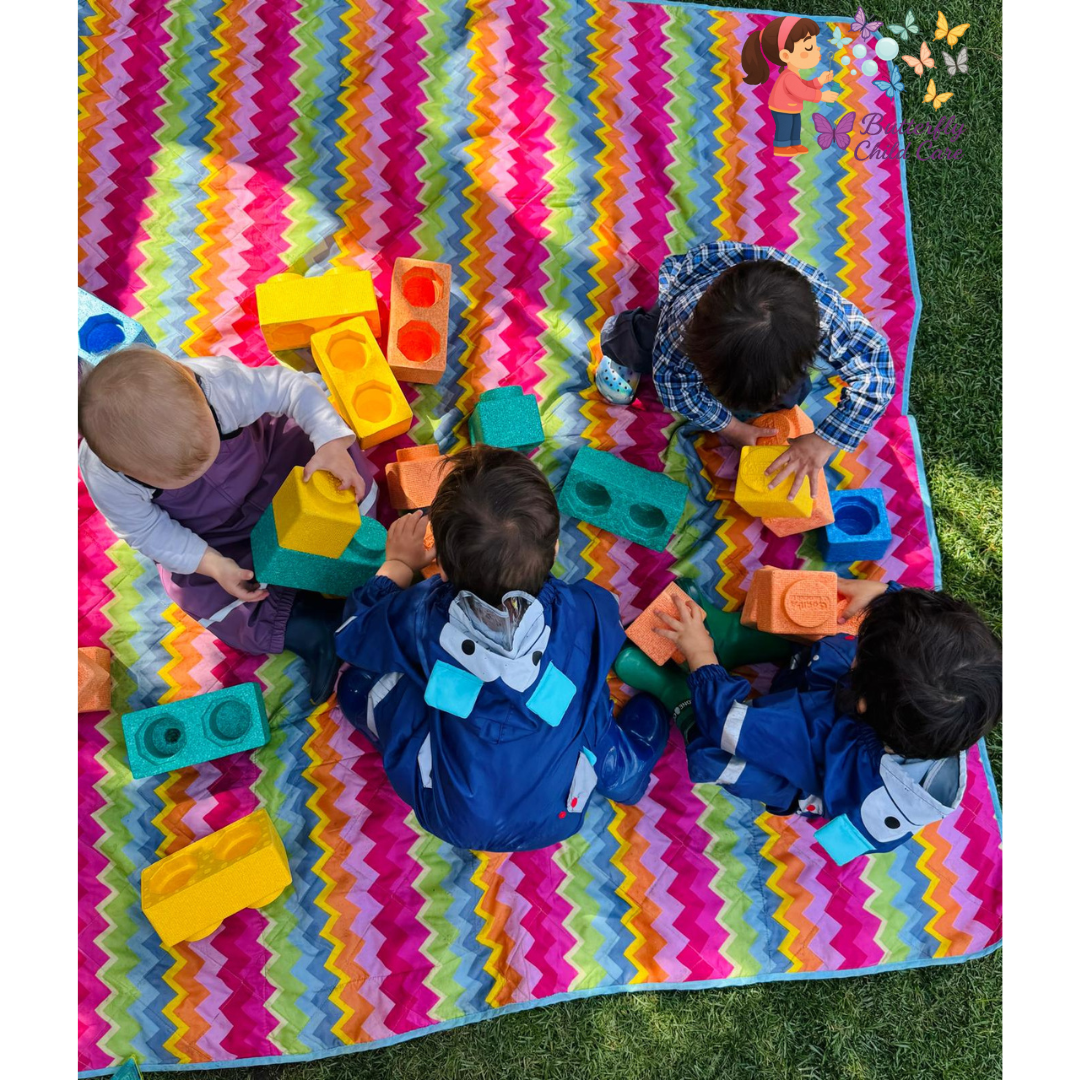 Toddlers playing with colorful foam blocks during outdoor sensory play at Butterfly Child Care